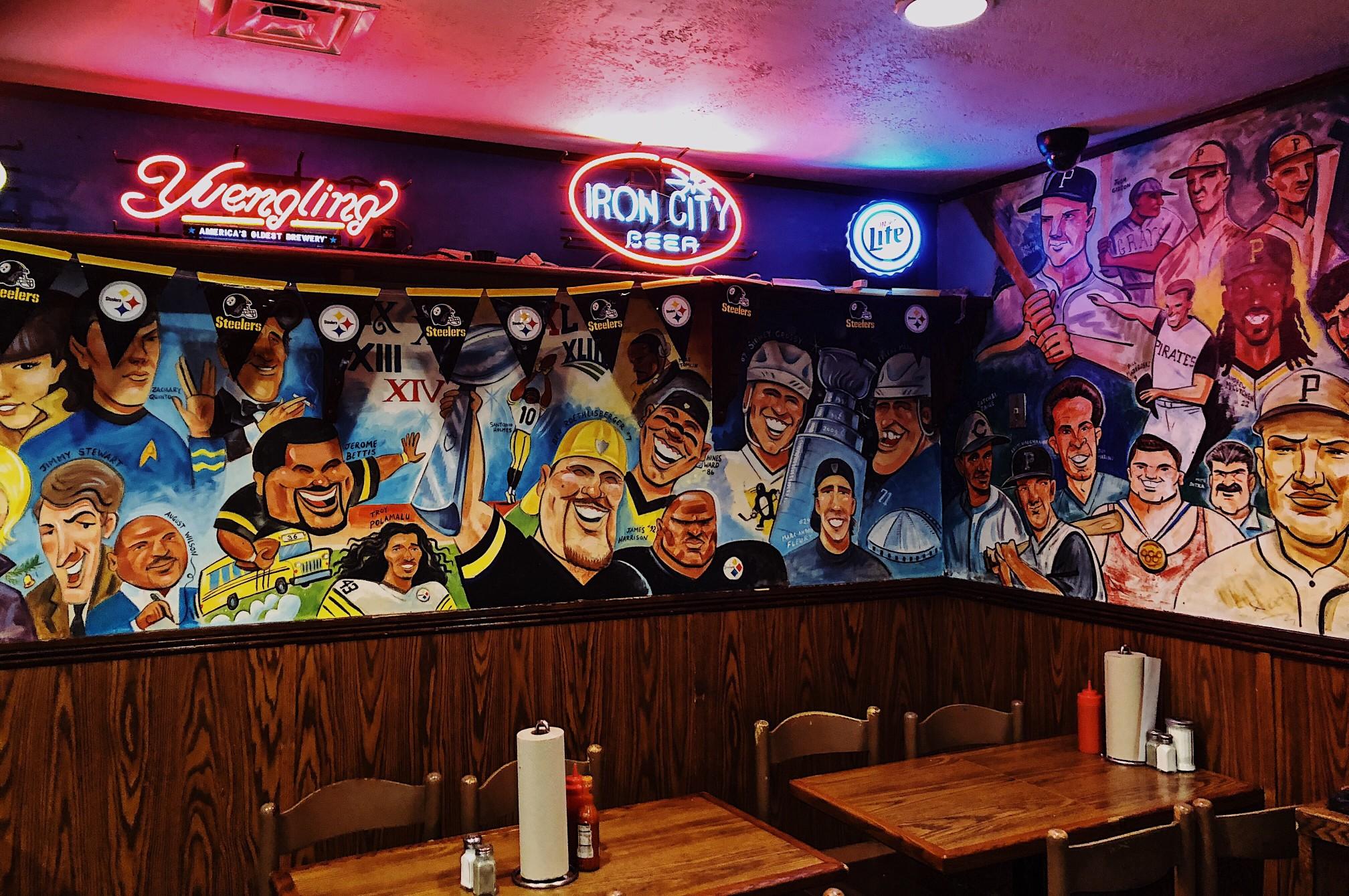 A mural featuring caricatures of famous Pennsylvania figures in Primanti Bros, Pittsburgh.