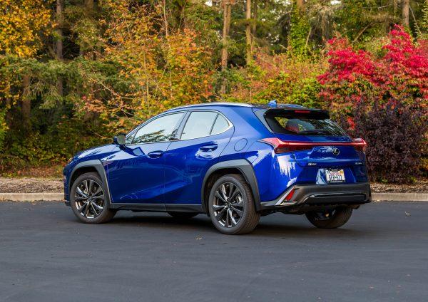 View of an ultrasonic blue mica UX parked in front of autumnal foliage. 