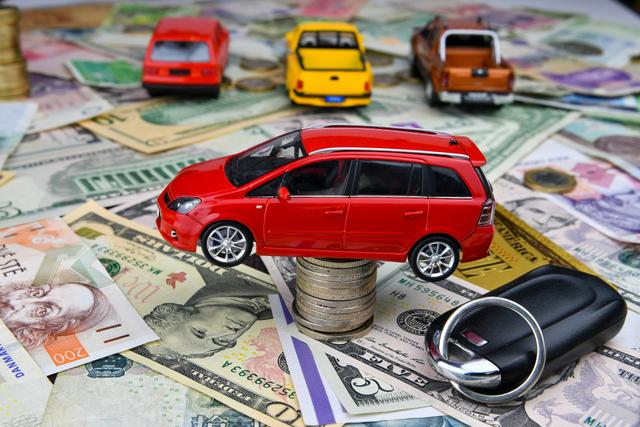 a-car-key-and-a-red-toy-car-on-a-tower-made-of-coins-background-of-various-national-currency-car_t20_P1yW38.jpg