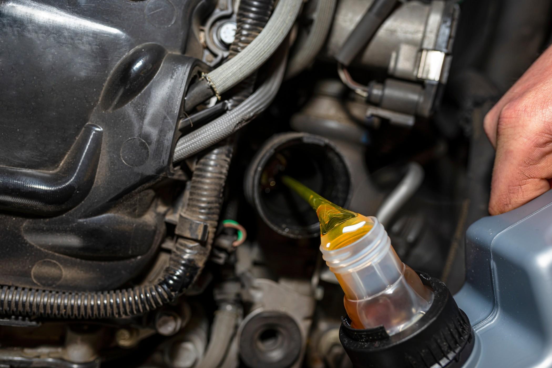 Fresh oil is poured into an engine during an oil change.