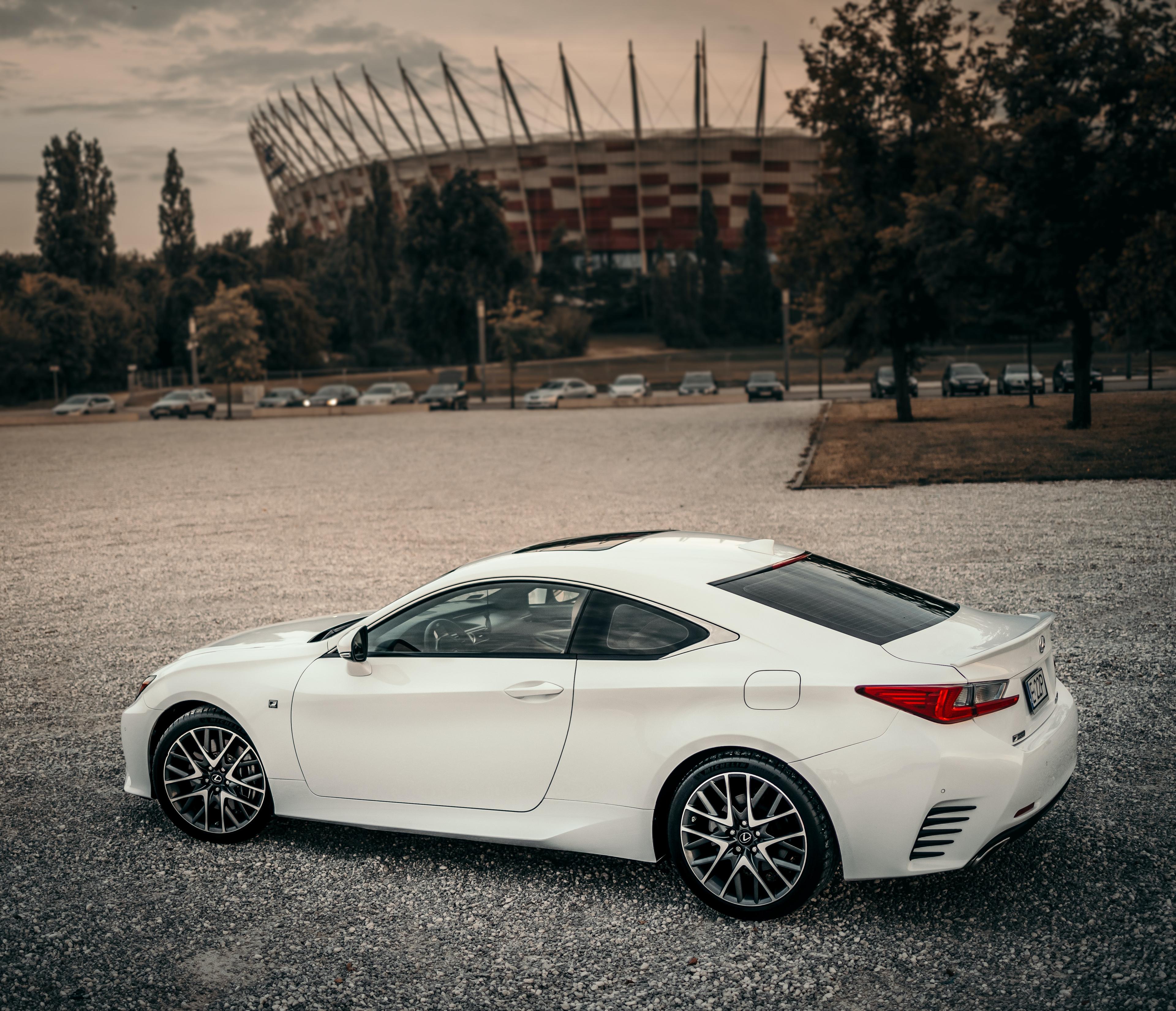 Image of a white RC Lexus, view from side and slightly above. Photo was taken in front of the Polish National Stadium in Warsaw and the stadium and more cars parked in the parking lot can be seen in the distance. 