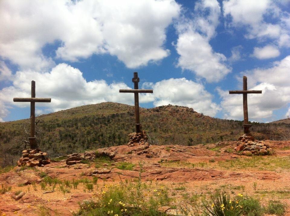 Three wooden crosses against a background of red rocks and a blue sky in Oklahoma.