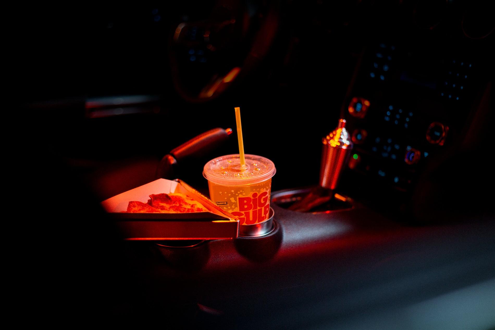Image of a Big Gulp in the drink holder, a slice of 711 pizza on the middle console and a slushy custom gearshift