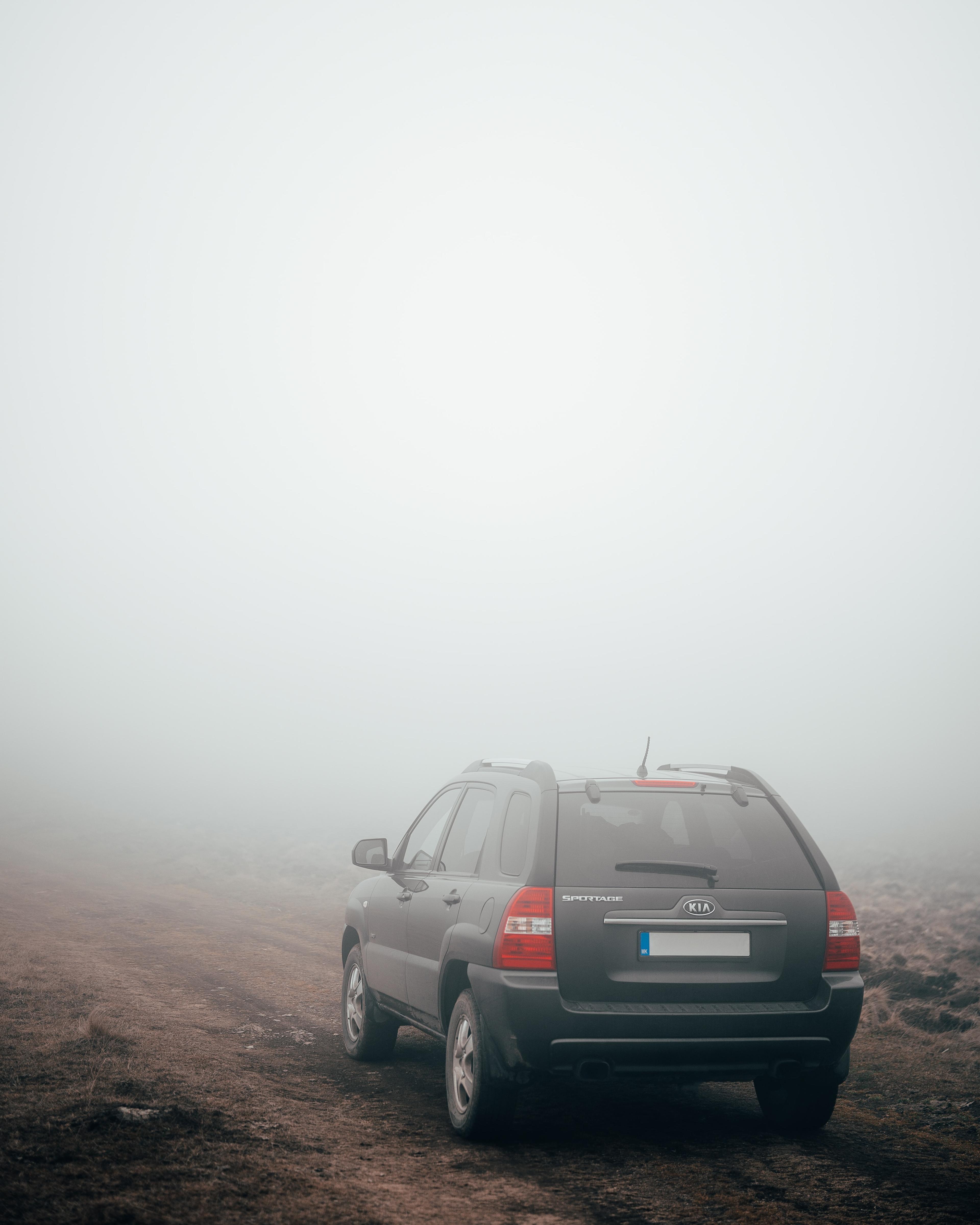 Image of a dark gray Kia Sportage driving through fog.