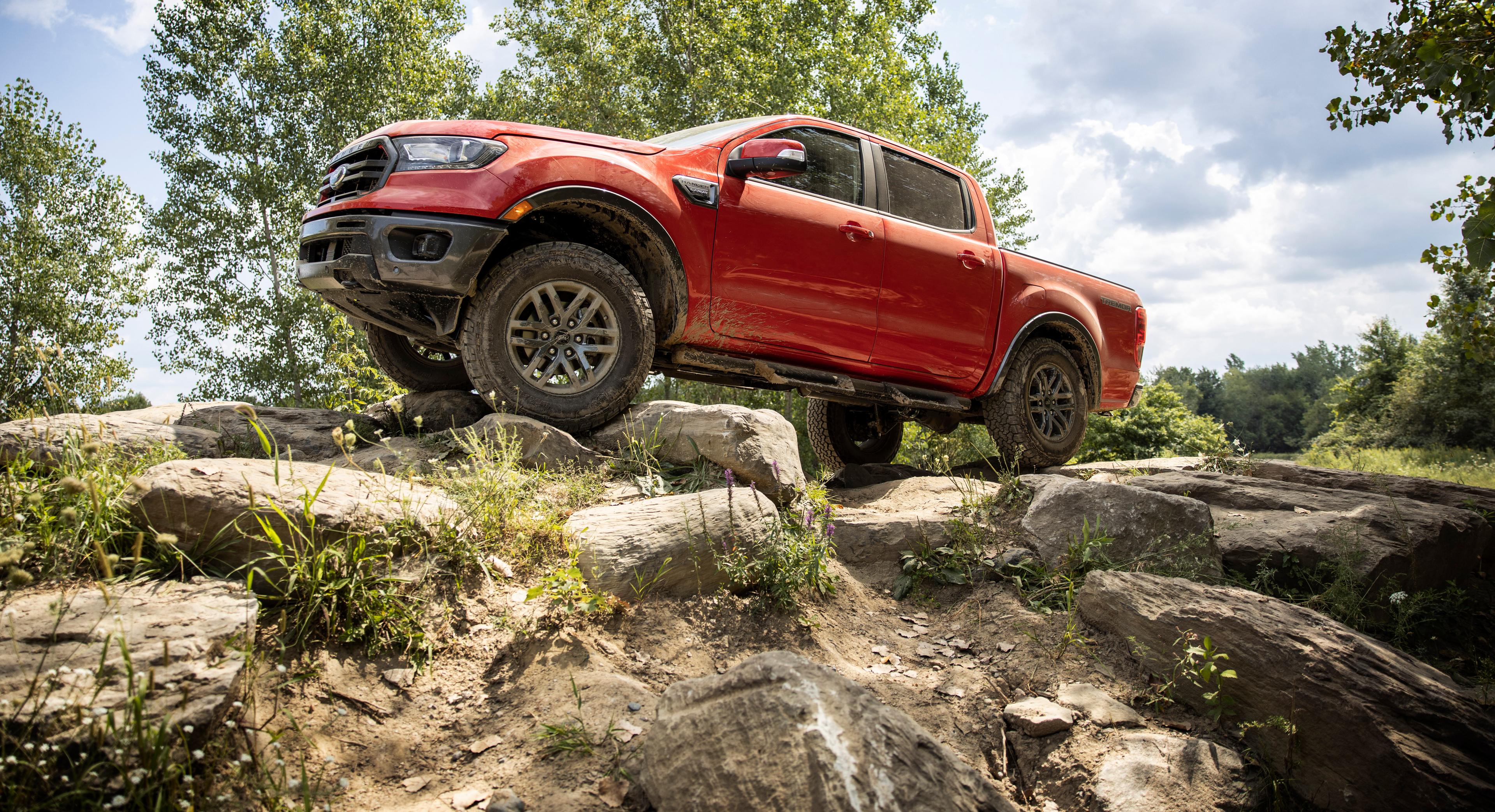 A red Ford anger off-roading on some large rocks 