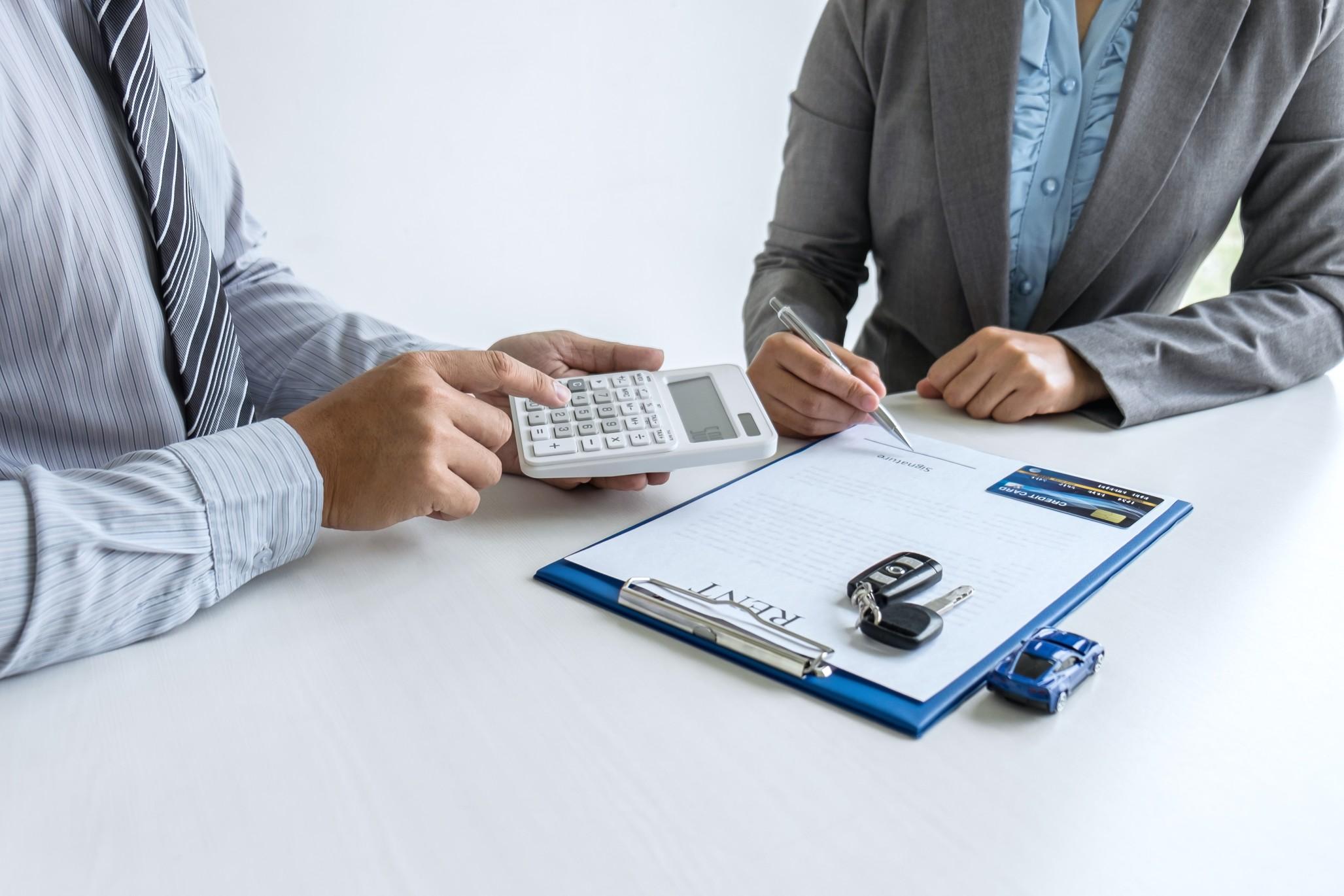 one man holding a calculator and one holding a pen ready to sign a rental contract 