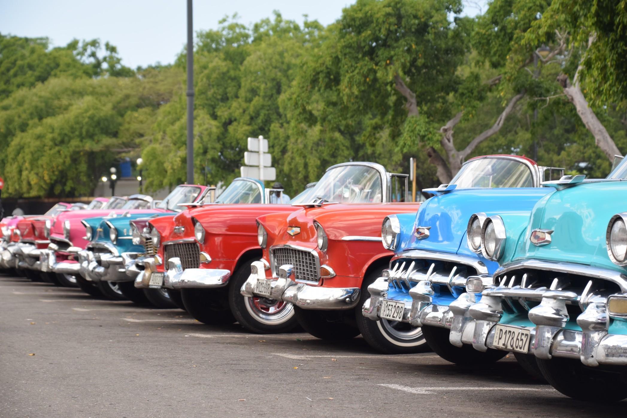 Colorful classic cars linedup in a parking lot.