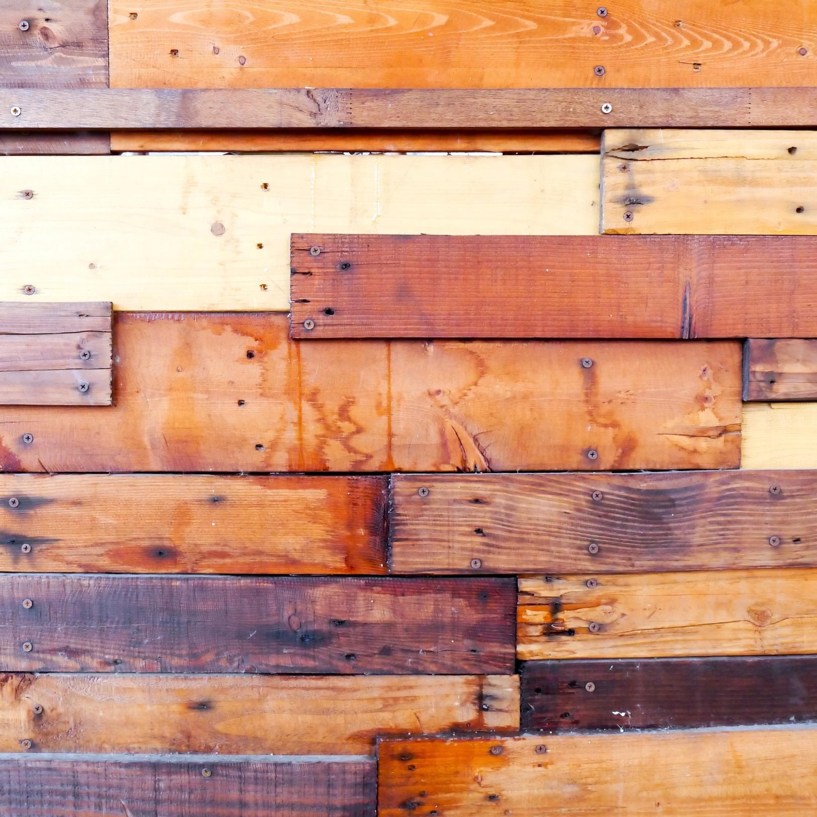 Wood planks of different sizes and colors arranged into a decorative fence.