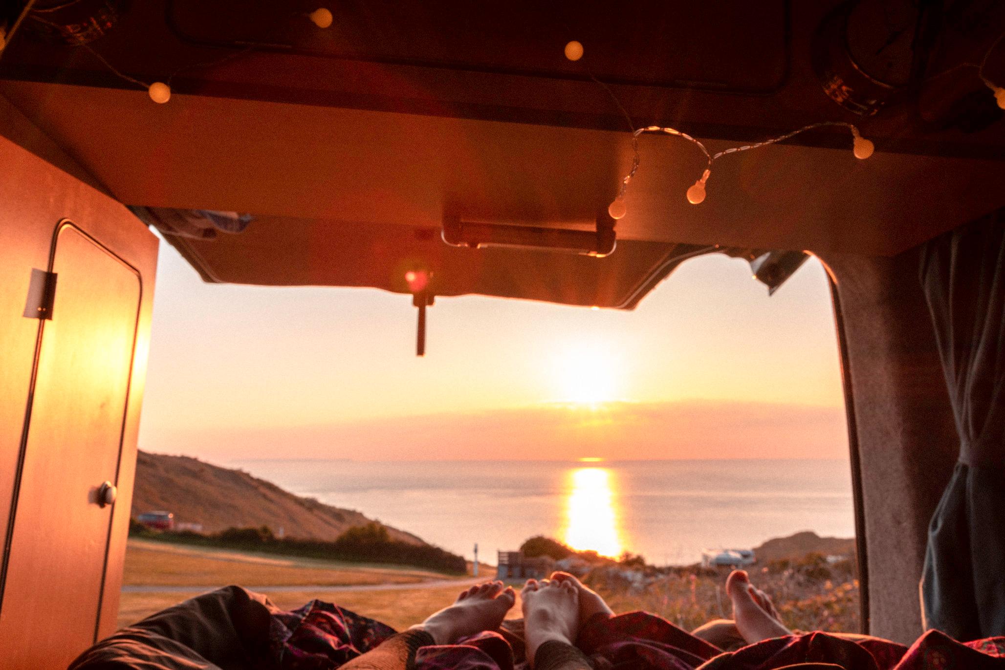 Two people watching a sunset out of their camper van.