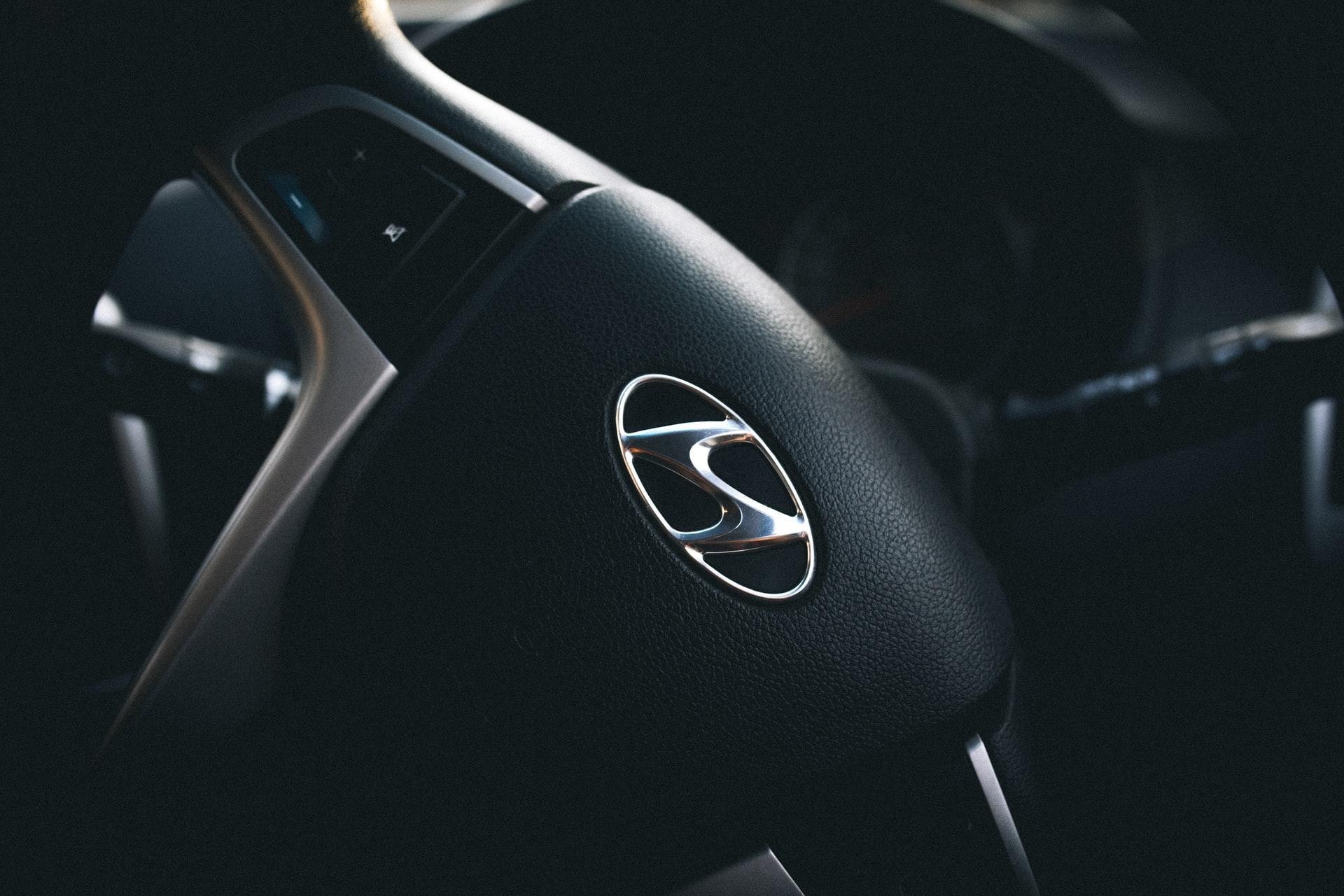A Hyundai logo on the steering wheel of car.