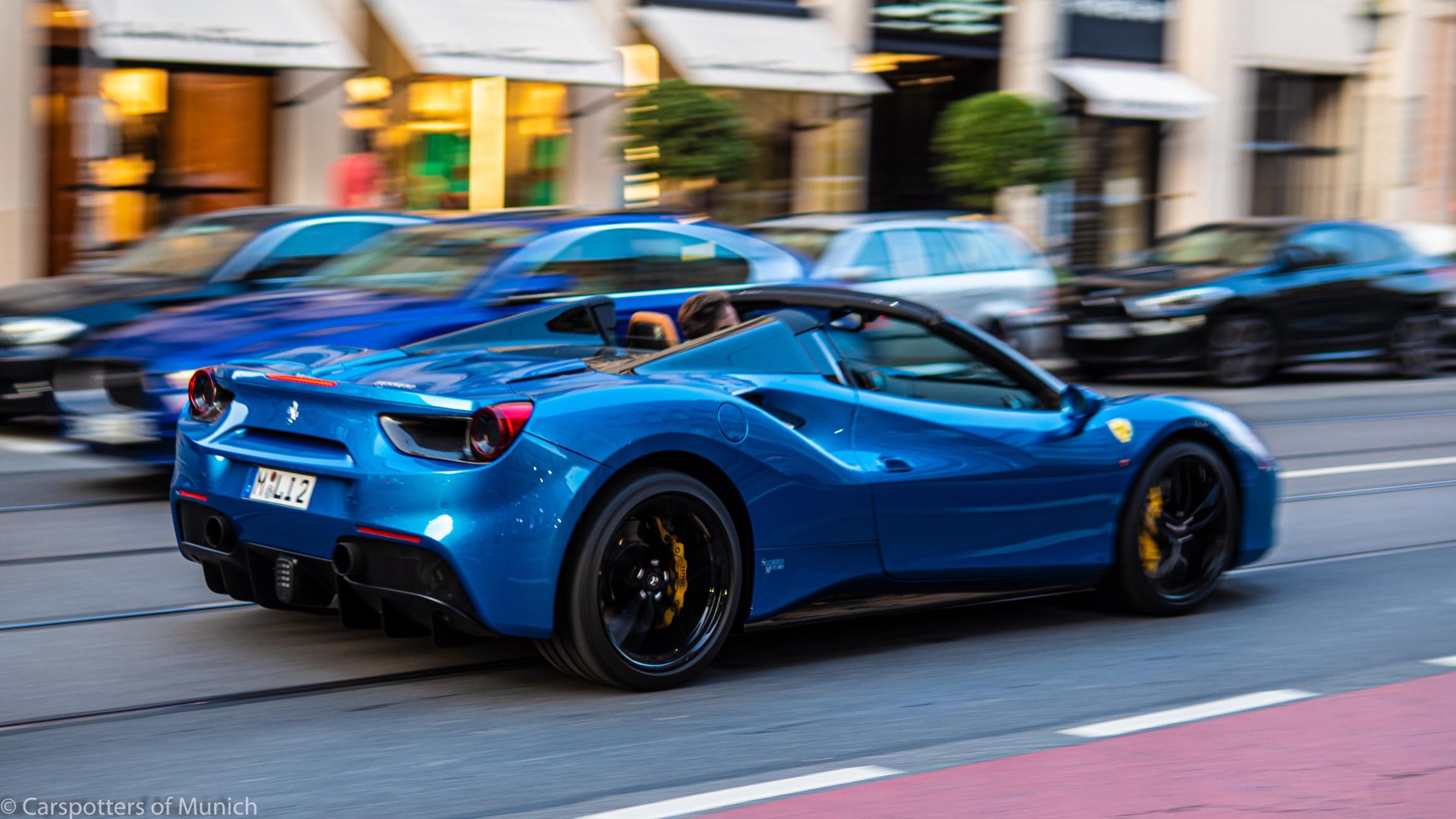 A blue Ferrari 488 Pista driving on a city street