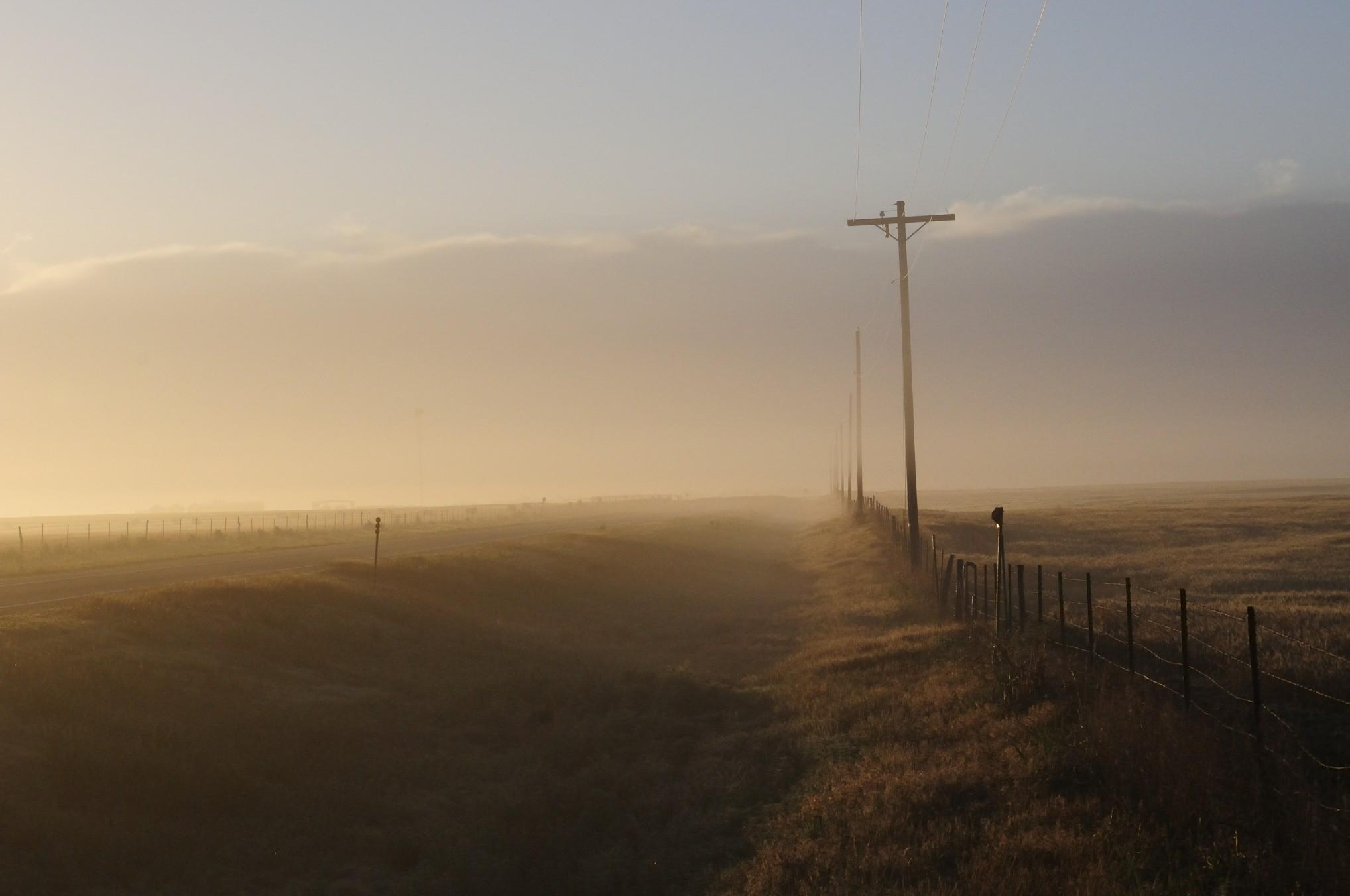 视图的字段和俄克拉何马州一个雾蒙蒙的早晨在农村的一条道路。