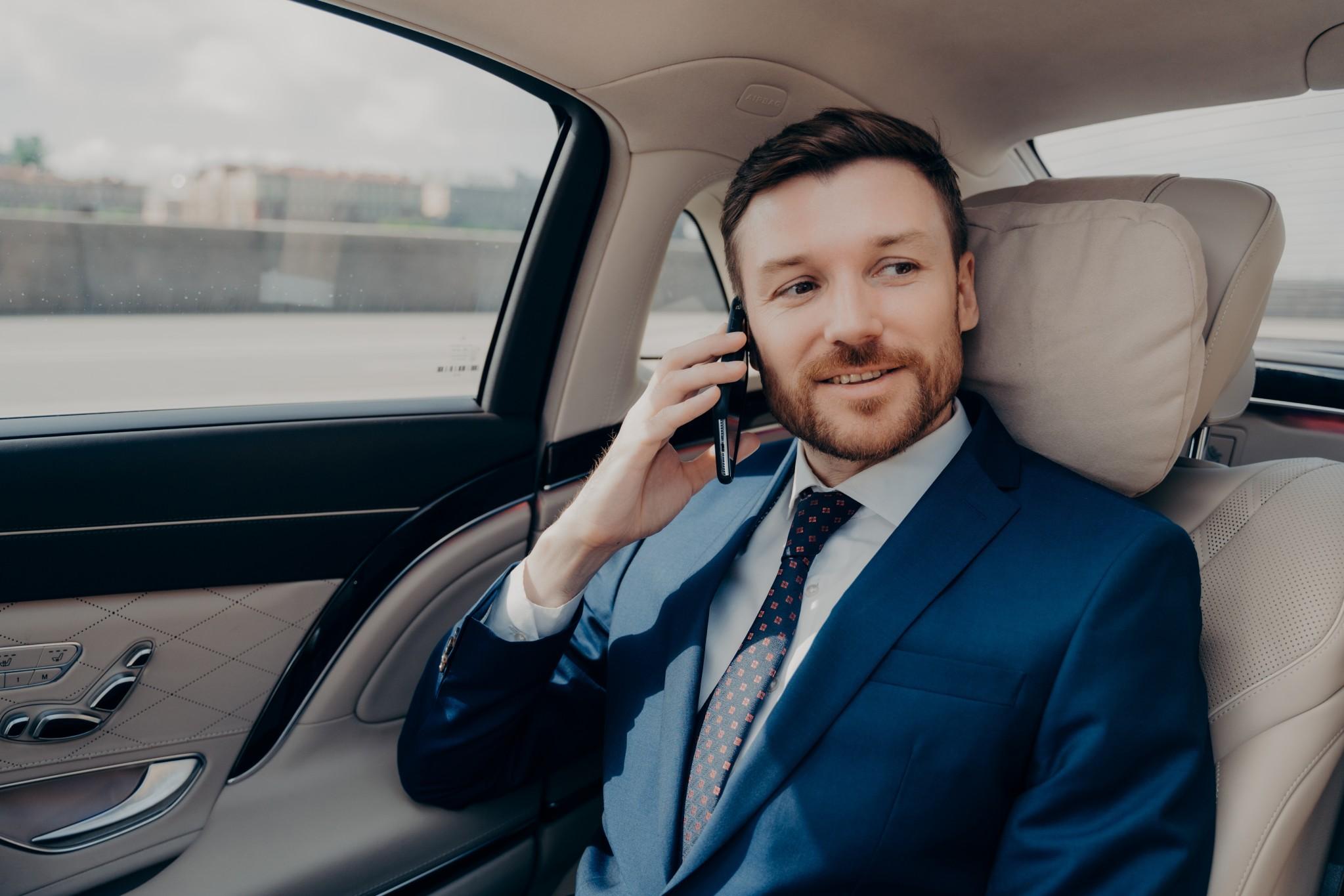 man in a business suit talking on a cell phone in a car